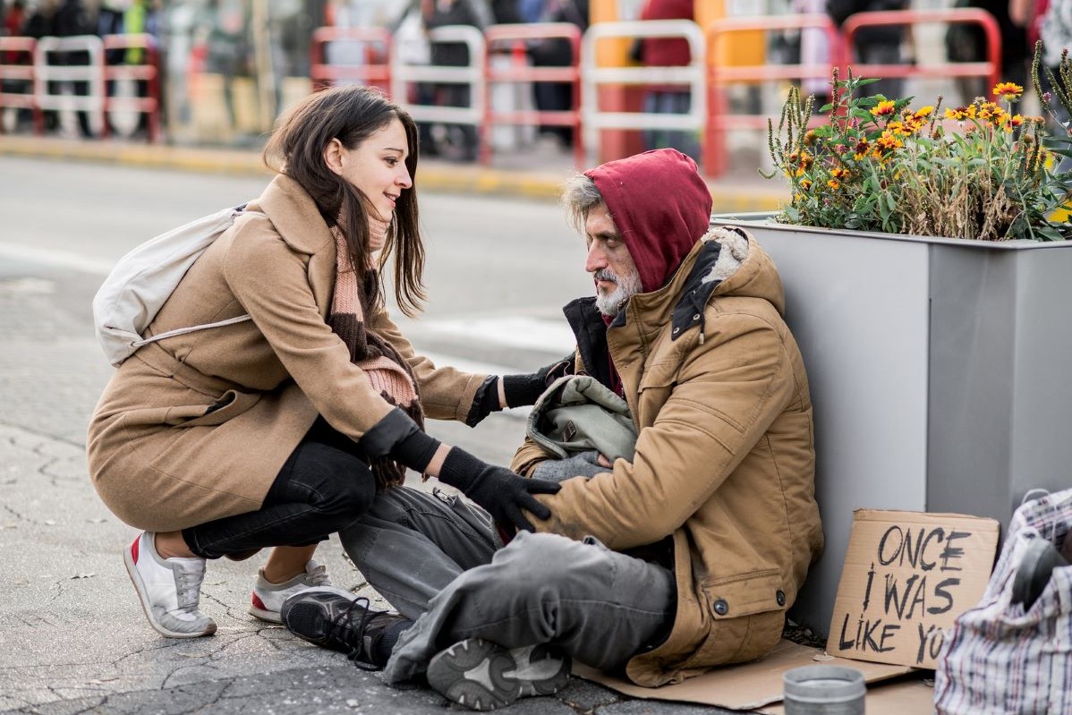 Alt=Woman helping a homeless man. 6 Dangers of resigning from God's assignment